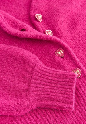 Luddig rosa kardiagan med hjärtformade guldknappar och ribbade muddar. Mjuk textur med en mysig design och livlig färg.