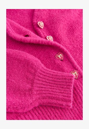 Luddig rosa kardiagan med hjärtformade guldknappar och ribbade muddar. Mjuk textur med en mysig design och livlig färg.