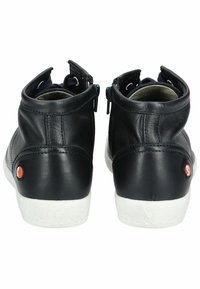 Botas de tobillo de cuero negro con suelas de goma blanca, dos cremalleras laterales y un acento de logo rojo en el talón. Textura suave con forma redondeada.