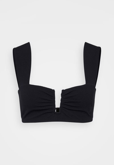 Fekete bandeau melltartó struktúrált szövetből, elől gyűrődésekkel, széles pántokkal és egy kis középső kivágással, amelyen fém részletek találhatók.