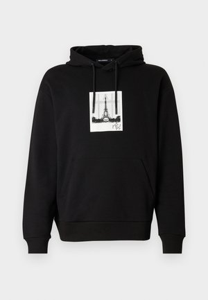 Sudadera negra con capucha ajustable y bolsillo frontal. Presenta un gráfico de la Torre Eiffel dentro de un borde rectangular blanco.