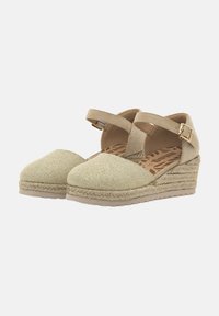 Zuecos de esparto beige con parte superior de tejido texturizado, tiras cruzadas con hebilla y media suela de yute trenzado. Suela de goma plana para mayor agarre.