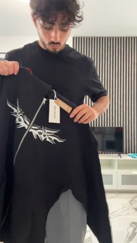 Felpa nera con zip e design grafico bianco. Etichetta attaccata con istruzioni per la cura. Tessuto morbido, design casual, maniche corte.