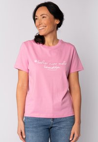 Rosa Baumwoll-T-Shirt mit kurzen Ärmeln und rundem Halsausschnitt, mit weißem Text, der "Früher war mehr Lametta" sagt.