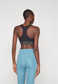 Puma KEEPS BRA - Športni modrček s srednjo podporo - black