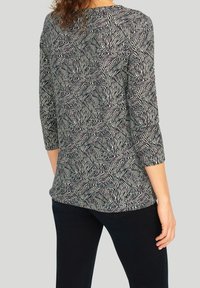 Bunt gemustertes Oberteil mit Dreiviertelärmeln. Verfügt über ein abstraktes Design in Schwarz, Weiß und Akzenten in Lila. Weiche Stofftextur.