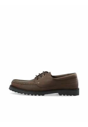 Chaussure bateau pour homme en cuir marron avec semelle en caoutchouc noire à crampons et fermeture à lacets à trois œillets, vue latérale sur fond blanc.