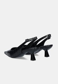 Tacones negros tipo slingback hechos de un material texturizado con relieve de cocodrilo; punta afilada, tacón bloque grueso y detalle de correa ajustable.