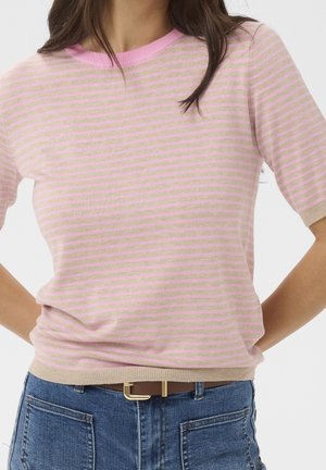 Femme portant un pull à manches courtes rayé rose et beige, rentré dans un jean bleu avec une ceinture marron à boucle dorée.