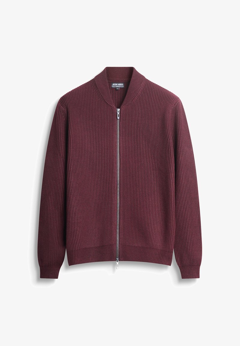 Bordo zip-up dukserica s rebrastom teksturom, s pojasom oko vrata i manžetama. Ima središnji patentni zatvarač i uski kroj.