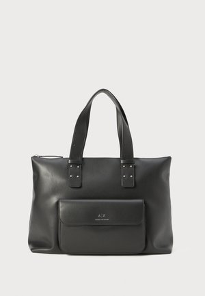 Black leather tote bag with two top handles, a front flap pocket, and silver hardware accents. Smooth texture and minimalist design.