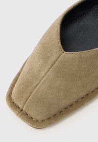 Chaussure en daim à enfiler de couleur marron clair avec un bout pointu, dotée d'un bord cousu et d'une doublure intérieure lisse noire.