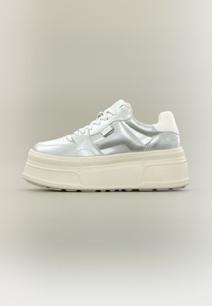 Chunky sneaker με μεταλλικό ασημί επάνω μέρος, λευκά κορδόνια και παχιά κρεμ χρωματιστή υφή σόλας, εμφανίζεται σε πλευρική όψη σε ουδέτερο φόντο.