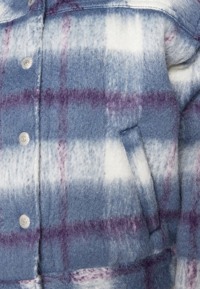 Veste en laine douce avec un motif en tartan bleu, blanc et violet, boutons-pression en métal et détail de poche latérale en biais.