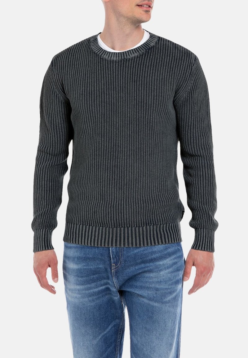 Maglione grigio scuro lavorato a maglia con una texture a coste, scollo rotondo e colletto a strisce in contrasto. Abbinato a jeans di denim blu.