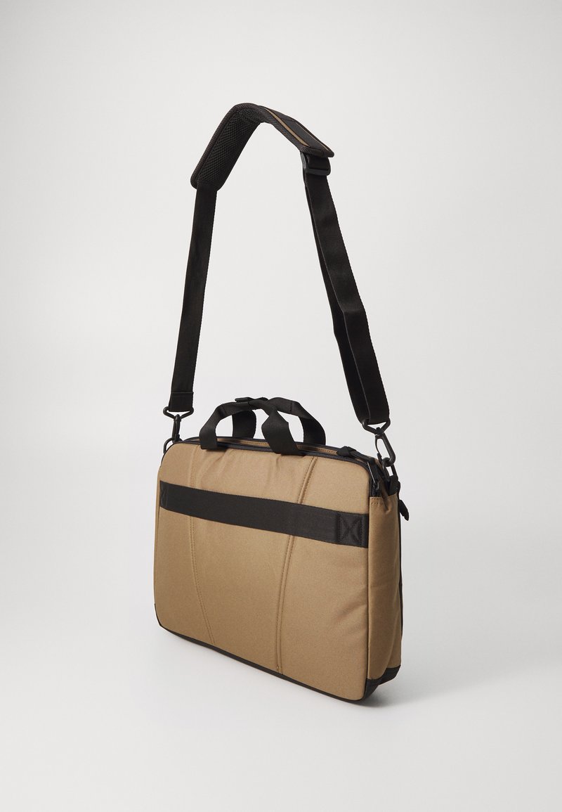 Laptoptasche aus beigefarbenem Stoff mit schwarzen Akzenten, ausgestattet mit einem gepolsterten Design, zwei oberen Traggriffen und einem abnehmbaren Schultergurt.