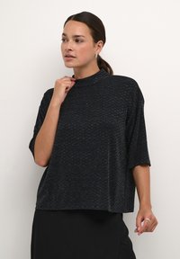 Top nero a maniche corte con colletto alto e vestibilità comoda. Tessuto testurizzato con un sottile motivo a macchie. Design semplice, senza dettagli aggiuntivi.