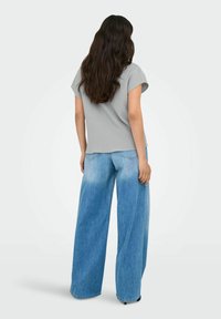 Maglietta short-sleeve grigia con texture abbinata a jeans larghi di colore azzurro chiaro con effetto sbiadito. Design semplice e casual senza motivi visibili.