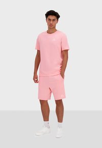 Set di t-shirt e pantaloni corti in cotone rosa, caratterizzato da una vestibilità comoda, scollatura a girocollo e dettaglio del logo. Abbinato a sneakers bianche.