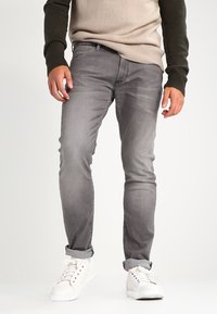 Grå denimjeans med slim fit, med subtila blekningar, fem fickor och uppvikta muddar. Matchas med vita sneakers.