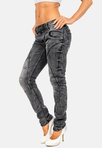 Jeans grigi in denim a vestibilità slim, con cuciture dettagliate e pannelli angolari. Abbinati a scarpe con tacco alto bianche.