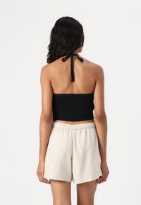 Μαύρο ραμπατέρ μπλουζάκι crop με ρυθμιζόμενο κορδόνι πίσω, συνδυασμένο με μπεζ σορτς από λινό ύφασμα που διαθέτουν ελαστική μέση.