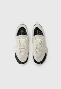 Beige Mesh-Sneaker mit schwarzer Gummisohle, grünen Akzenten, runder Spitze und elastischen Schnürsenkeln. Mit einer Schlaufe an der Ferse für ein einfaches An- und Ausziehen.