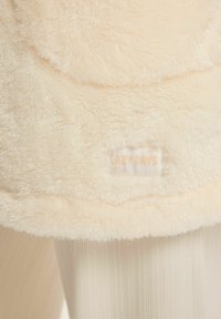 Fuzzy cream blanket featuring a soft texture, rounded edges, and a label reading "LAZY DAYS" in subtle lettering.