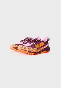 Des chaussures de sport violettes et roses avec des accents orange, présentant une semelle texturée, un design à lacets et un motif de semelle intermédiaire moucheté.