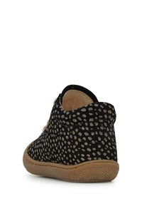 Scarpa in tessuto nero con motivo a pois testurizzati, interno morbido e suola in gomma. Presenta un design a caviglia bassa e dettagli cuciti.