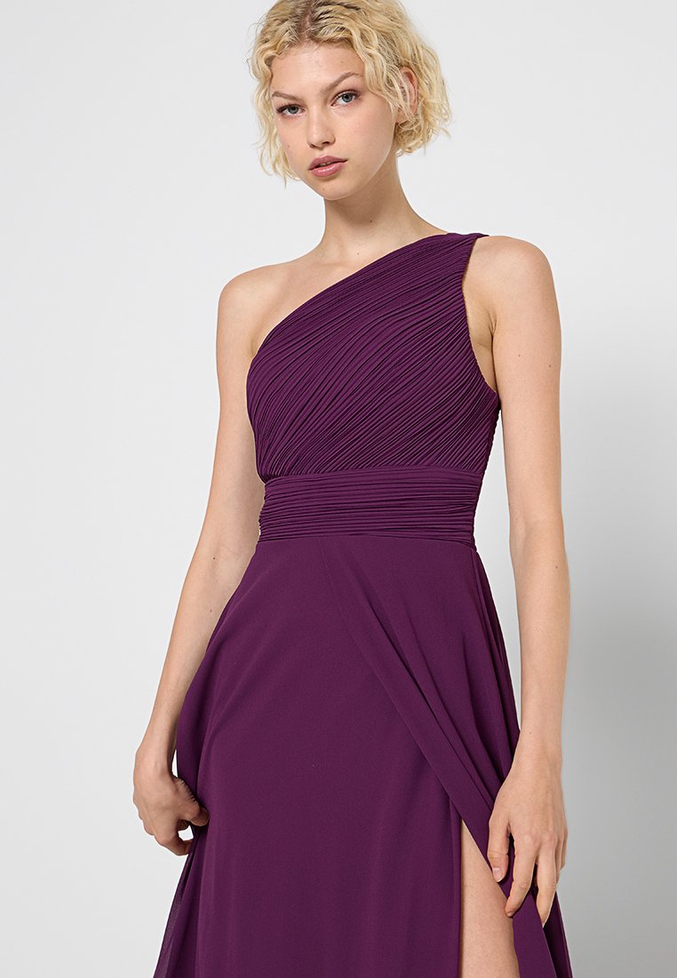 Asymmetrisches lila Kleid mit geraffter Textur oben, drapiertem Stoff und einem Oberschenkel-hohen Schlitz auf der Seite. Glattes Material aus Polyester-Mischung.