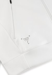 Felpa bianca con zip, caratterizzata da un tessuto testurizzato, polsini a coste e stampa del logo sul lato inferiore.