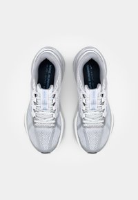 Graue Laufschuhe verfügen über ein atmungsaktives Obermaterial aus Mesh mit einem strukturierten Muster, weißen Schnürsenkeln und einer gepolsterten Sohle. Das Nike-Logo befindet sich auf der Zunge.