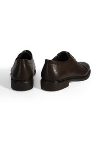Bruine leren dresschoenen met een gladde afwerking, ronde neus, vetersluiting en een lage zwarte rubberen zool. Kenmerkt subtiele stikselaccenten.