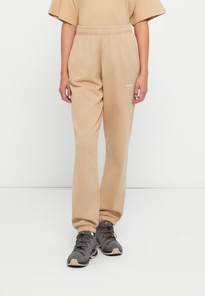 Beige joggingsbroeken gemaakt van zachte stof, met een elastische tailleband, zijzakken en taps toelopende boorden bij de enkels.