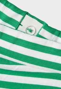 Tissu rayé vert et blanc avec une maille texturée. Comprend un bouton à la taille et une étiquette cousue à l'arrière.