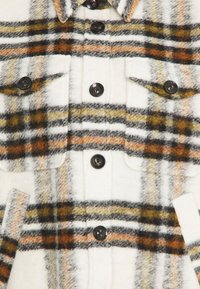 Kariertes Wollhemd-Jackett mit einem Farbschema in Weiß, Schwarz, Orange und Gelb, sechs schwarzen Knöpfen und zwei Brusttaschen.