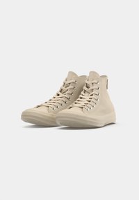 Beige hoogtop sneakers van canvas met metalen oogjes, platte veters, rubberen zolen en gestructureerde teentips.