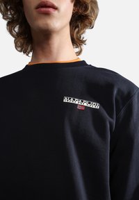 Sudadera navy con cuello redondo acanalado, interior del cuello en naranja contrastante y pequeño logo bordado en blanco con emblema de bandera roja en el pecho.
