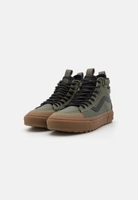 Høye sneakers med et grønt tekstiloverdel, svarte lisser, såle i naturgummi og teksturerte detaljer. Unike sømmer på sidene.