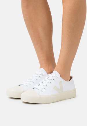 Weiße Leinensneaker mit beigen Gummisohlen, die ein großes beiges "V"-Logo an der Seite und ein klassisches Schnürdesign aufweisen.