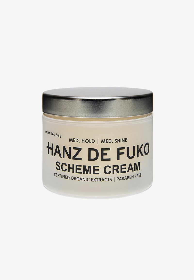 Duidelijke glazen pot met een zilverkleurig metalen deksel, gelabeld "Hanz de Fuko Scheme Cream," bevat een lichte crème. Netto gewicht: 56 g. Parabene vrij.