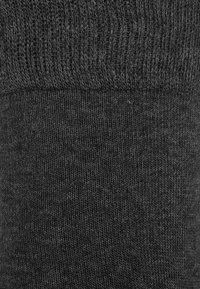 Dunkelgraue Socke mit rippenförmigem Bund, glatter Textur und nahtlosem Design. Das Material zeigt ein feines Strickmuster mit leicht variierender Farbnuance.