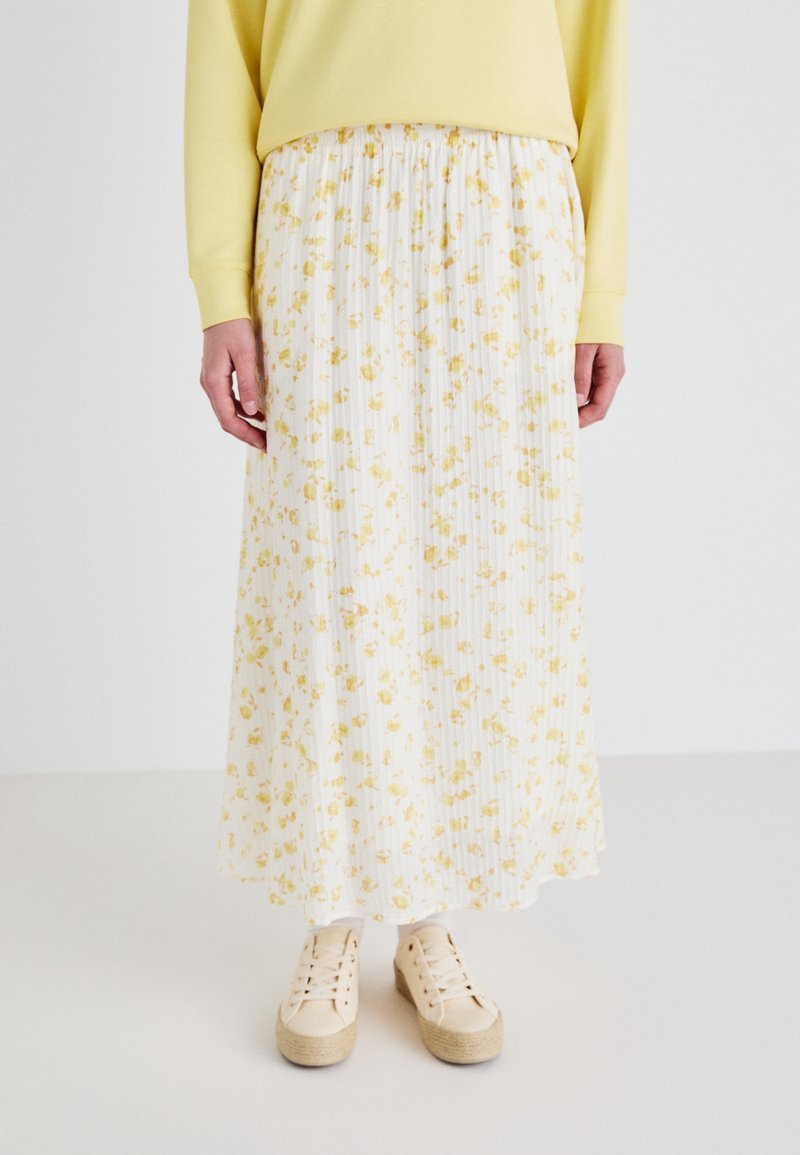 Maxi rok met bloemenprint in geel en wit, geplooid ontwerp, gemaakt van lichte stof. Gepaard met beige platform sneakers.