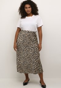 Jupe midi imprimée léopard avec une taille élastique, en tissu lisse et léger. Associée à un t-shirt blanc uni et des ballerines noires.