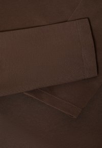 Bruine lange mouwen shirtstof met een gladde textuur, voorzien van een platte kraag en zichtbare stiksels langs de mouwranden.