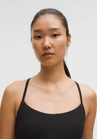 Fekete ujjatlan felső vékony pántokkal, sima anyagból, minimalista dizájnnal és lekerekített neckline-nel, alkalmas hétköznapi viseletre vagy réteges öltözködéshez.