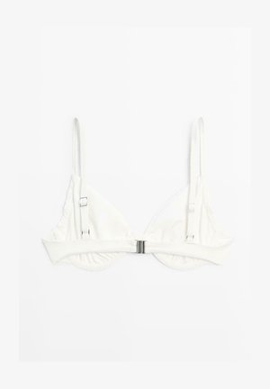 Hvid justerbar bh med tynde stropper og en metallåse foran på en ensfarvet hvid baggrund.