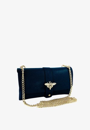 Zwarte textuurlook clutch met gouden bijvormige sluiting en lange gouden kettingriem ernaast op witte achtergrond opgerold.