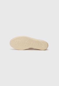 Sole di scarpa color crema con battistrada texturizzato e motivi circolari, con il nome del marchio impresso sul fondo per una migliore aderenza e trazione.